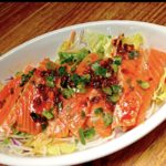 Raw Salmon with hot chili oil on top and shredded cabbage under them.