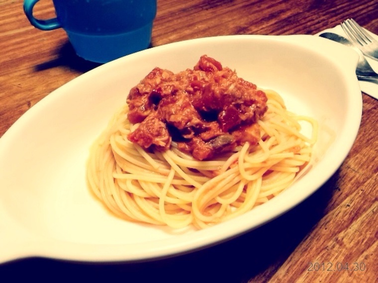 Spaghetti with cooked bacon on top in white plate