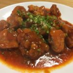 Ketchup based chili sauce on top of deep fried chicken. Sliced green onions on top.